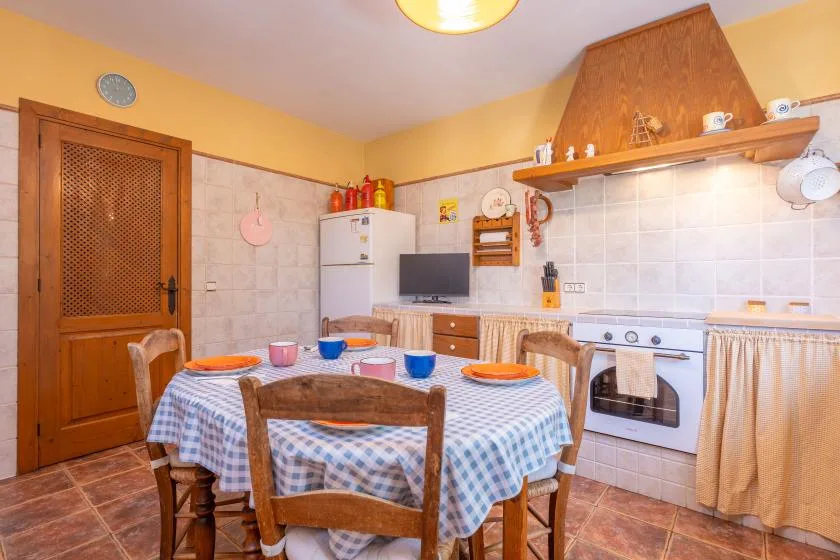 A kitchen and dining area with a checkered tablecloth and cooking range.