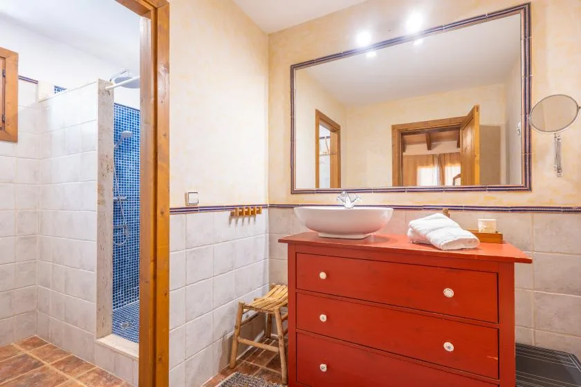 A bathroom with a red vanity, sink, and large wall mirror.