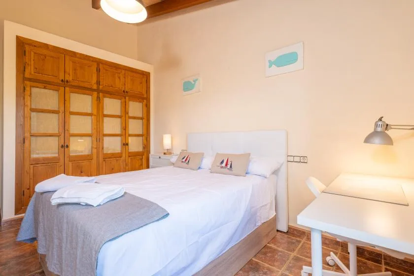 A bedroom with a bed, wooden wardrobe, and desk.