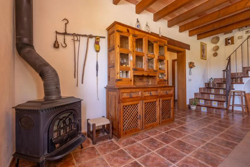 A rustic living area features a wood-burning stove beside a large wooden cabinet.