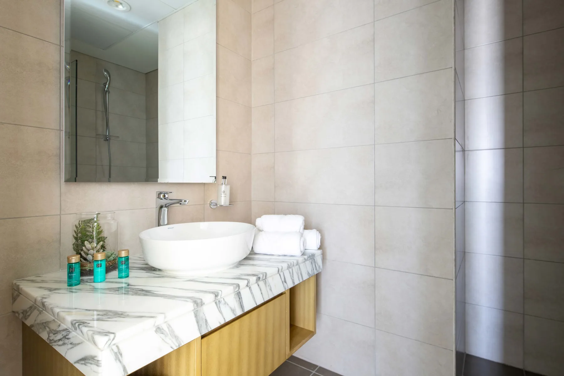 A tiled bathroom with a vessel sink and folded towels on the counter.