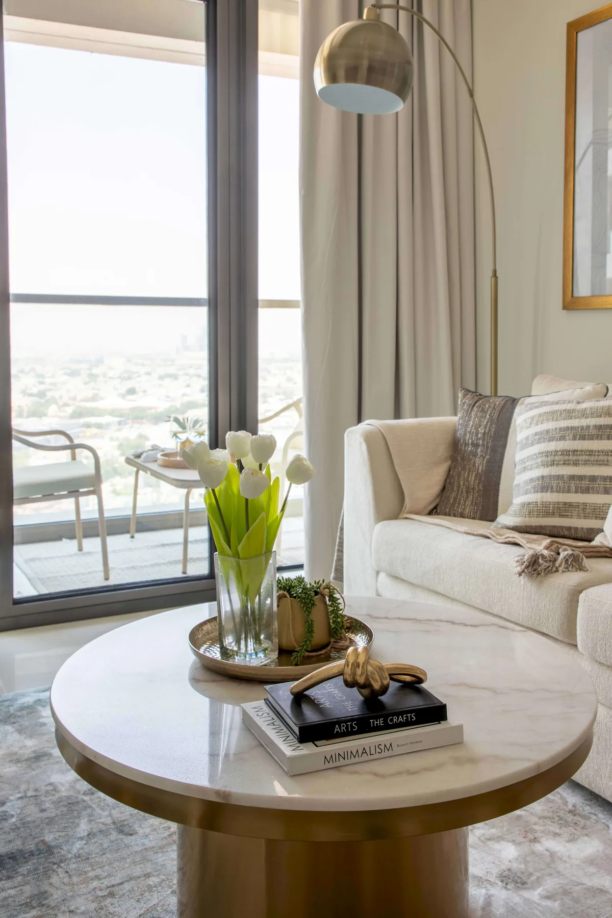 A living room with a seating area, a round coffee table, and tall windows.