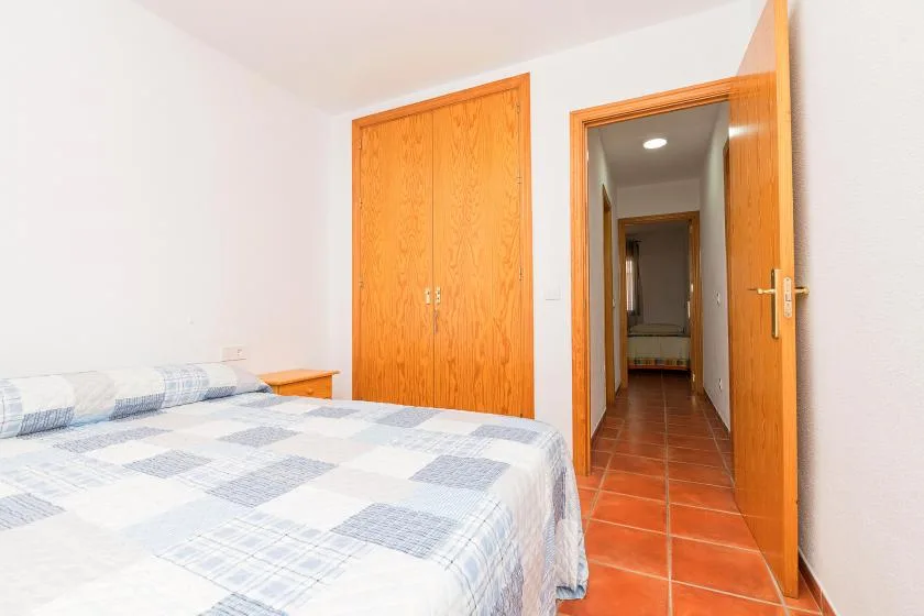 Un dormitorio con una cama, un armario de madera y una puerta abierta.