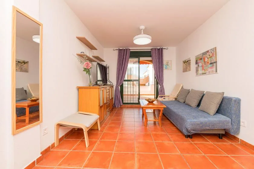 Una sala de estar con asientos, una mesa de centro y puertas de vidrio que dan a un balcón.