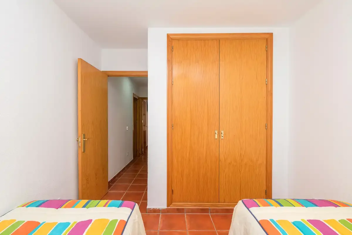 Un dormitorio con dos camas y un armario de madera.
