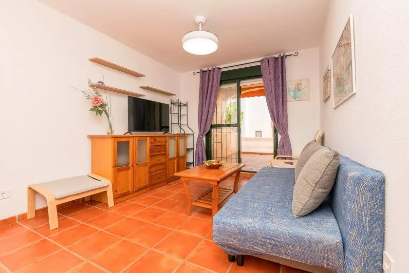 Una sala de estar con asientos, una mesa de centro de madera y una puerta de cristal al balcón.
