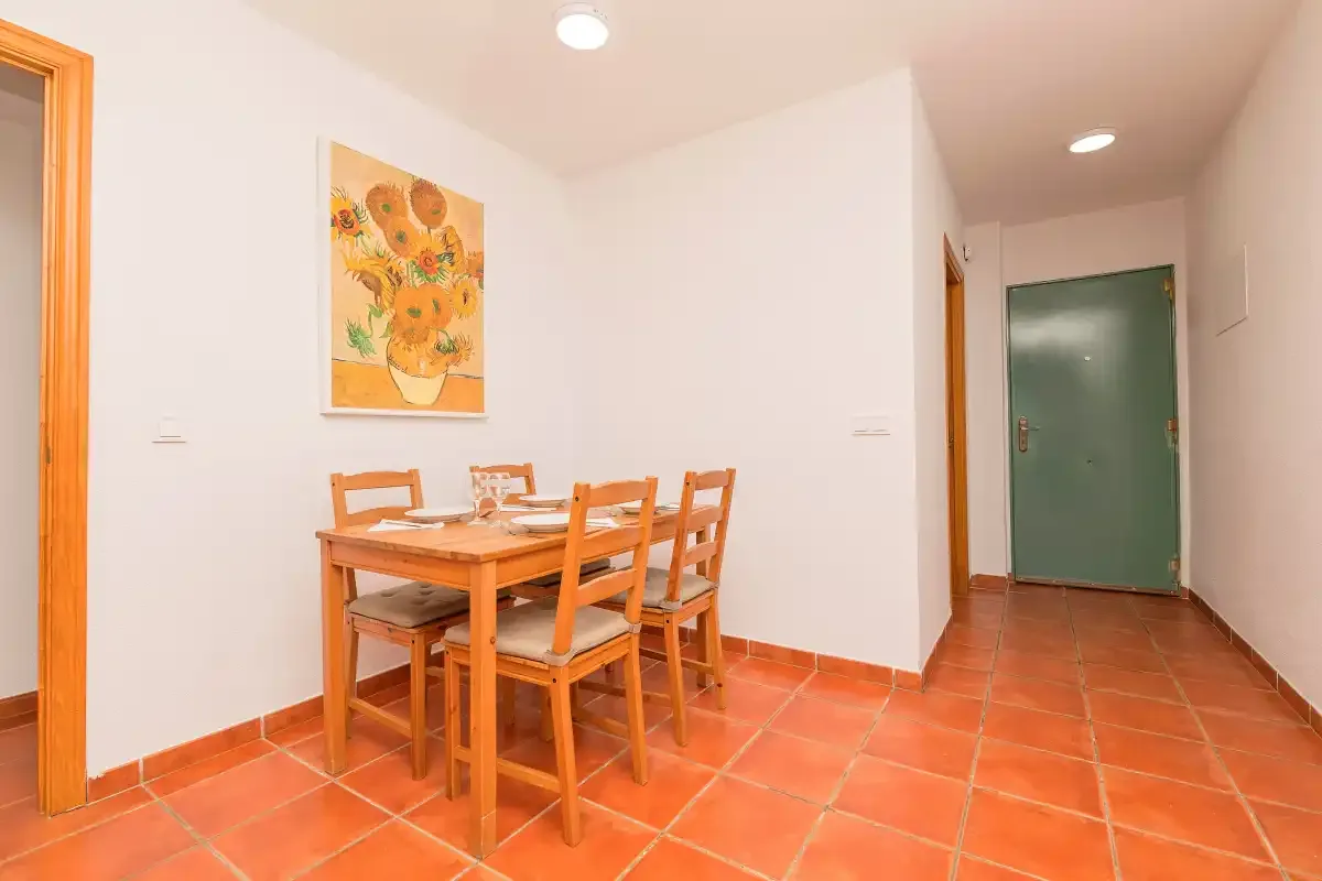 Comedor con una mesa de madera y sillas junto a un pasillo.