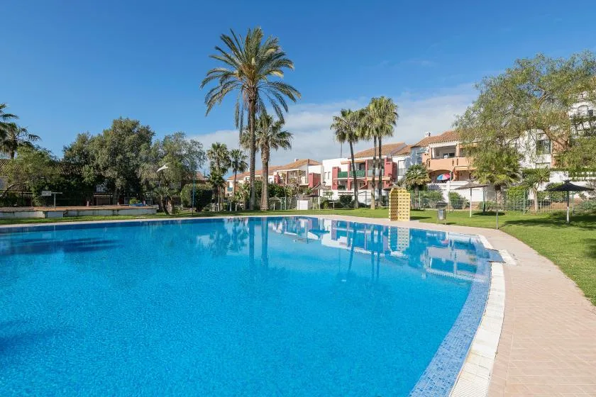 A large outdoor swimming pool sits beside a paved walkway and landscaped grounds.