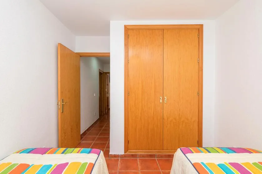 Un dormitorio con ropa de cama a rayas de colores y un armario de madera.