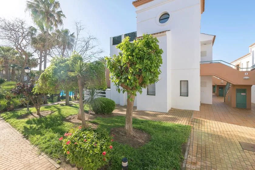 Un edificio blanco junto a un jardín cuidado y un camino pavimentado.