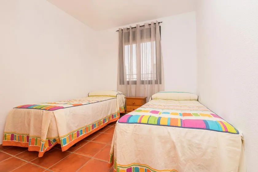 Un dormitorio con dos camas bajo una ventana con cortinas.