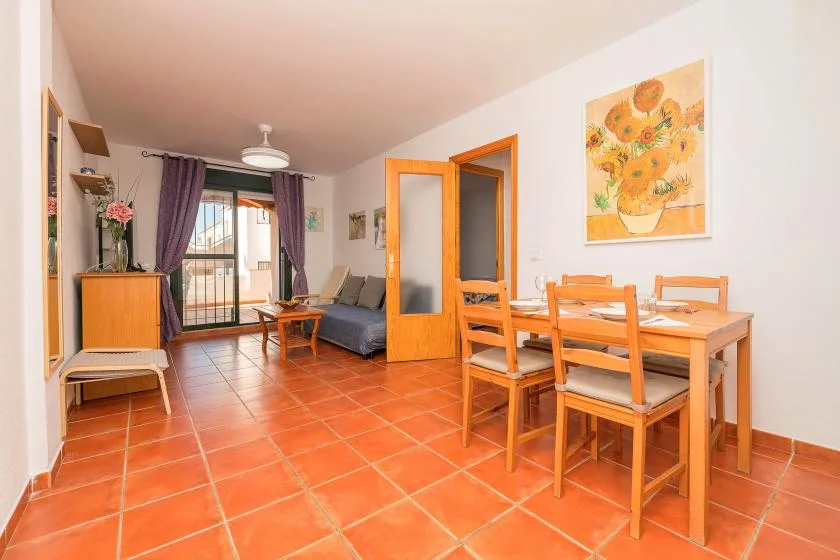 Sala de estar y comedor con una mesa y asientos junto a las puertas de cristal.