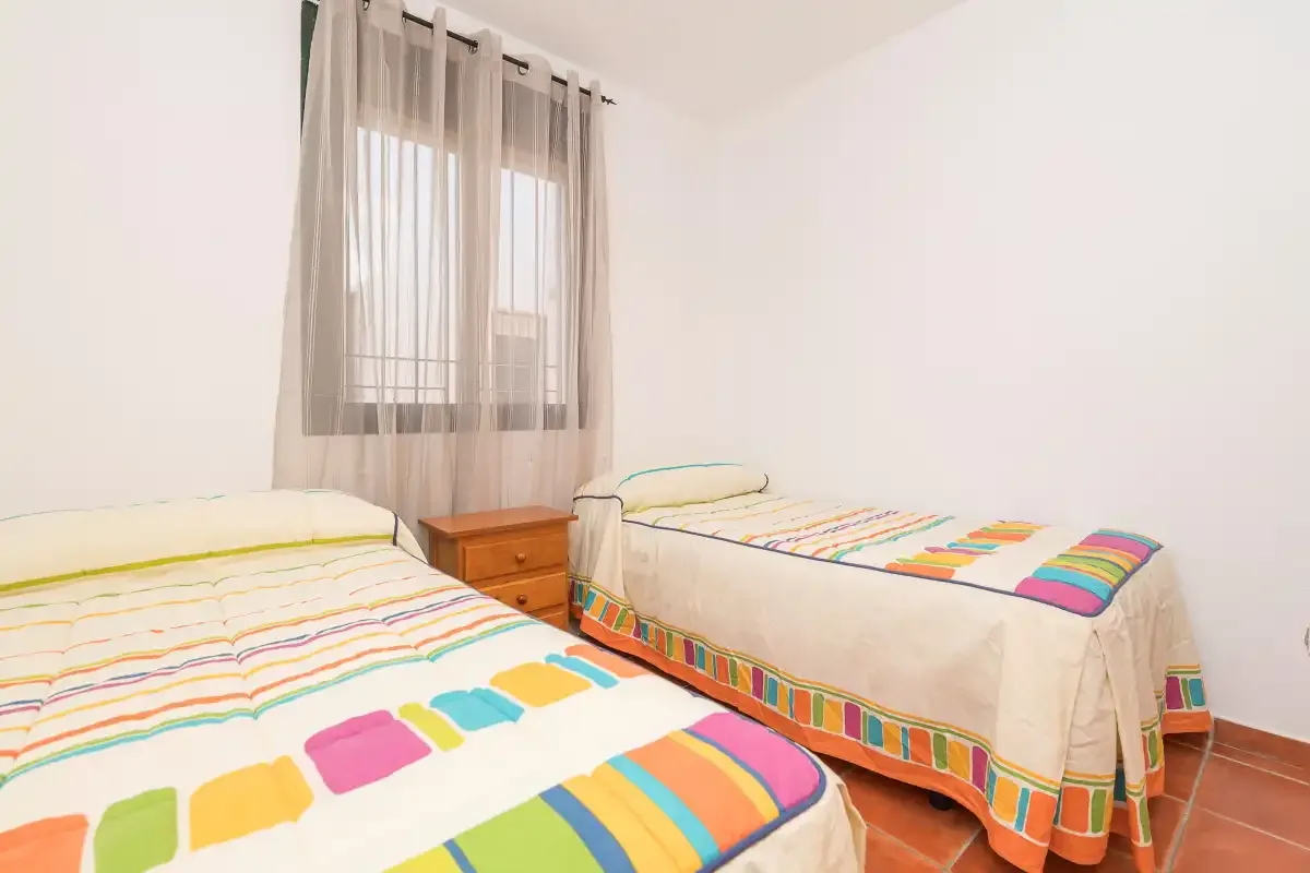 Un dormitorio con dos camas vestidas con ropa de cama a rayas de colores.