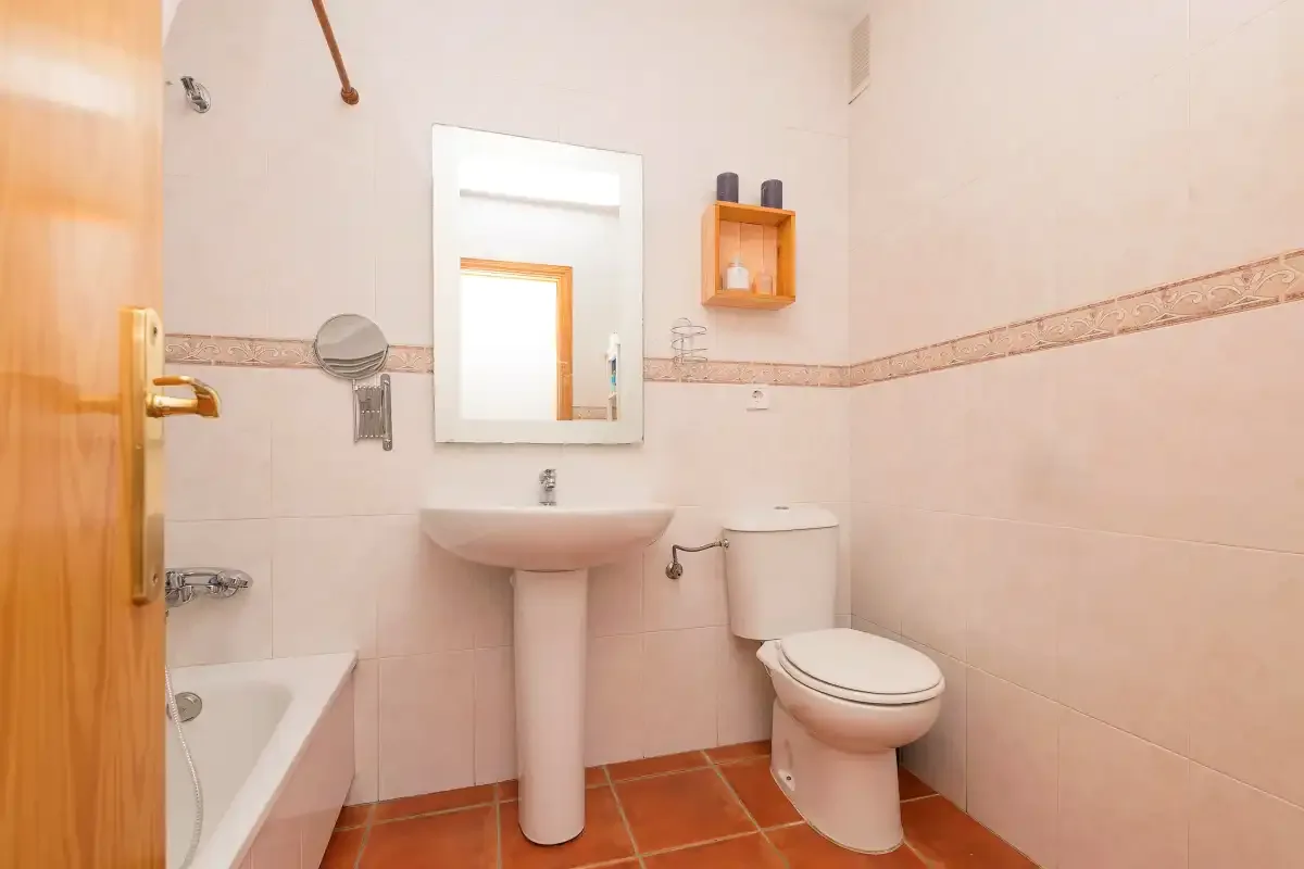Un baño con azulejos, lavabo, espejo, inodoro y bañera.