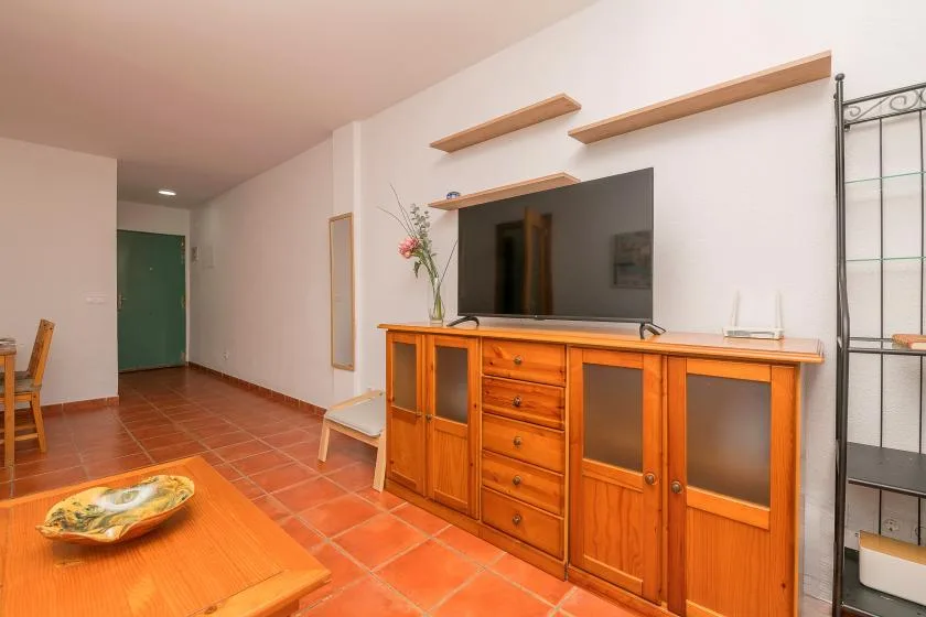 Una sala de estar con un televisor sobre un mueble de madera y una mesa baja.