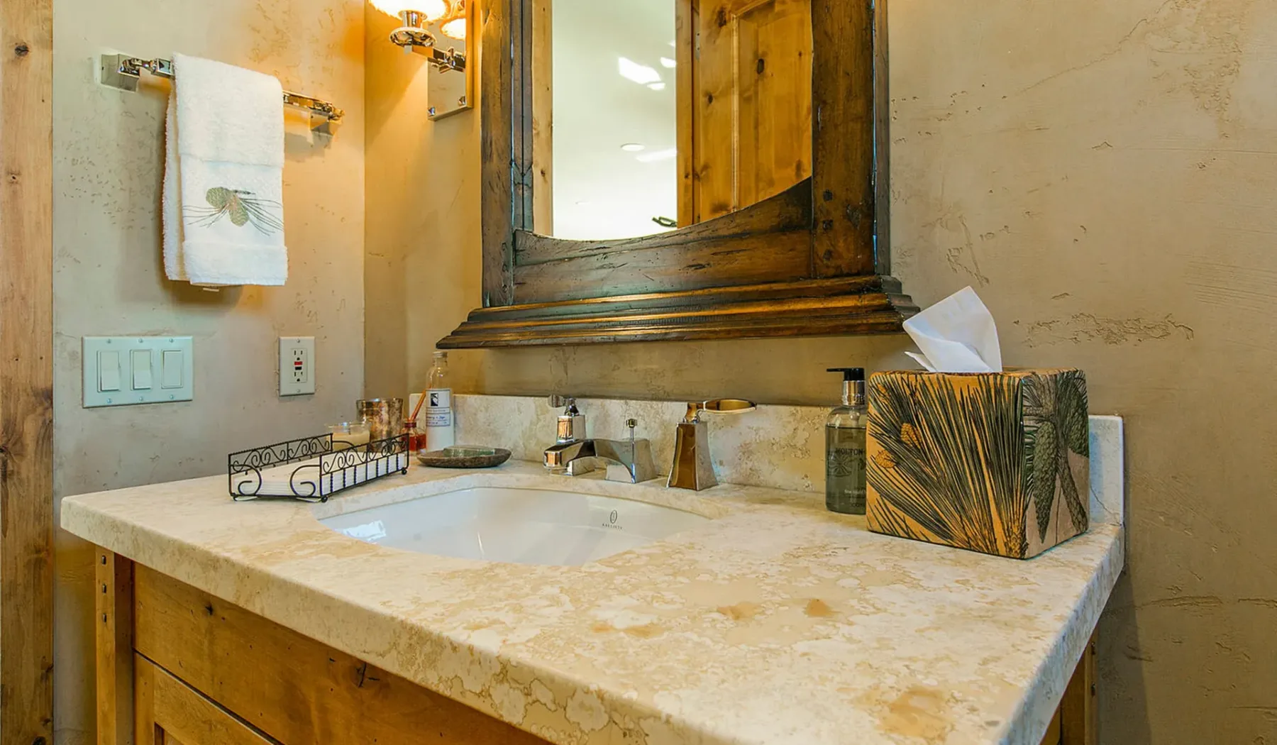 Un tocador de baño con lavabo está bajo un espejo con marco de madera.