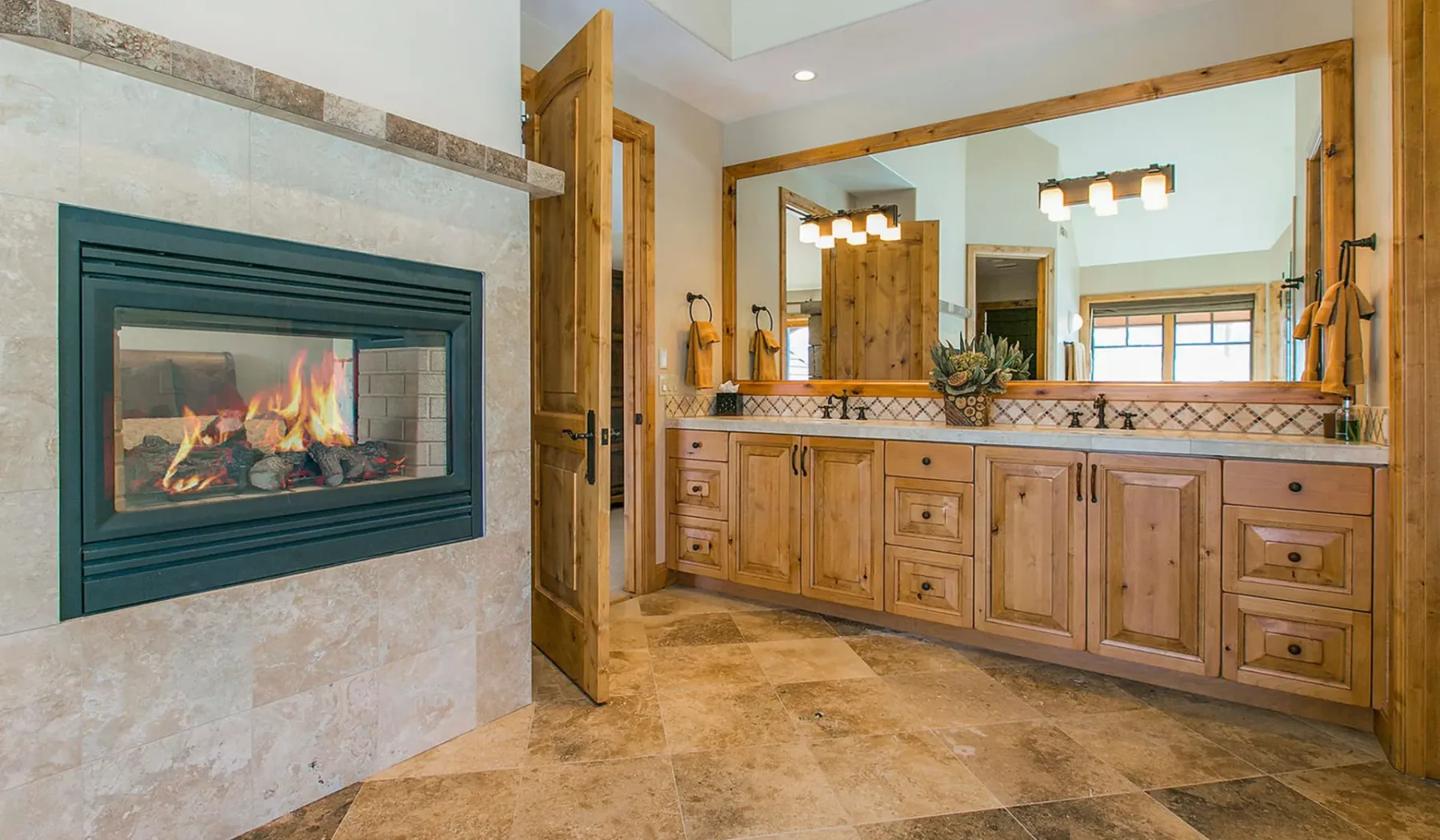 Un lavabo de baño con un espejo amplio está junto a una chimenea empotrada.