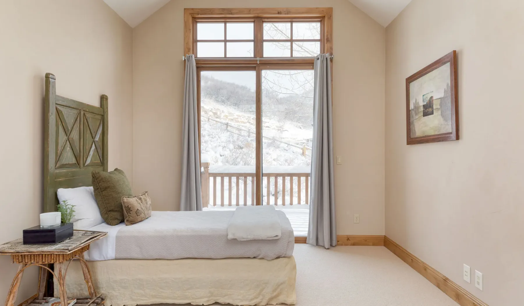 Dormitorio con una cama junto a una ventana grande con vistas a la montaña.
