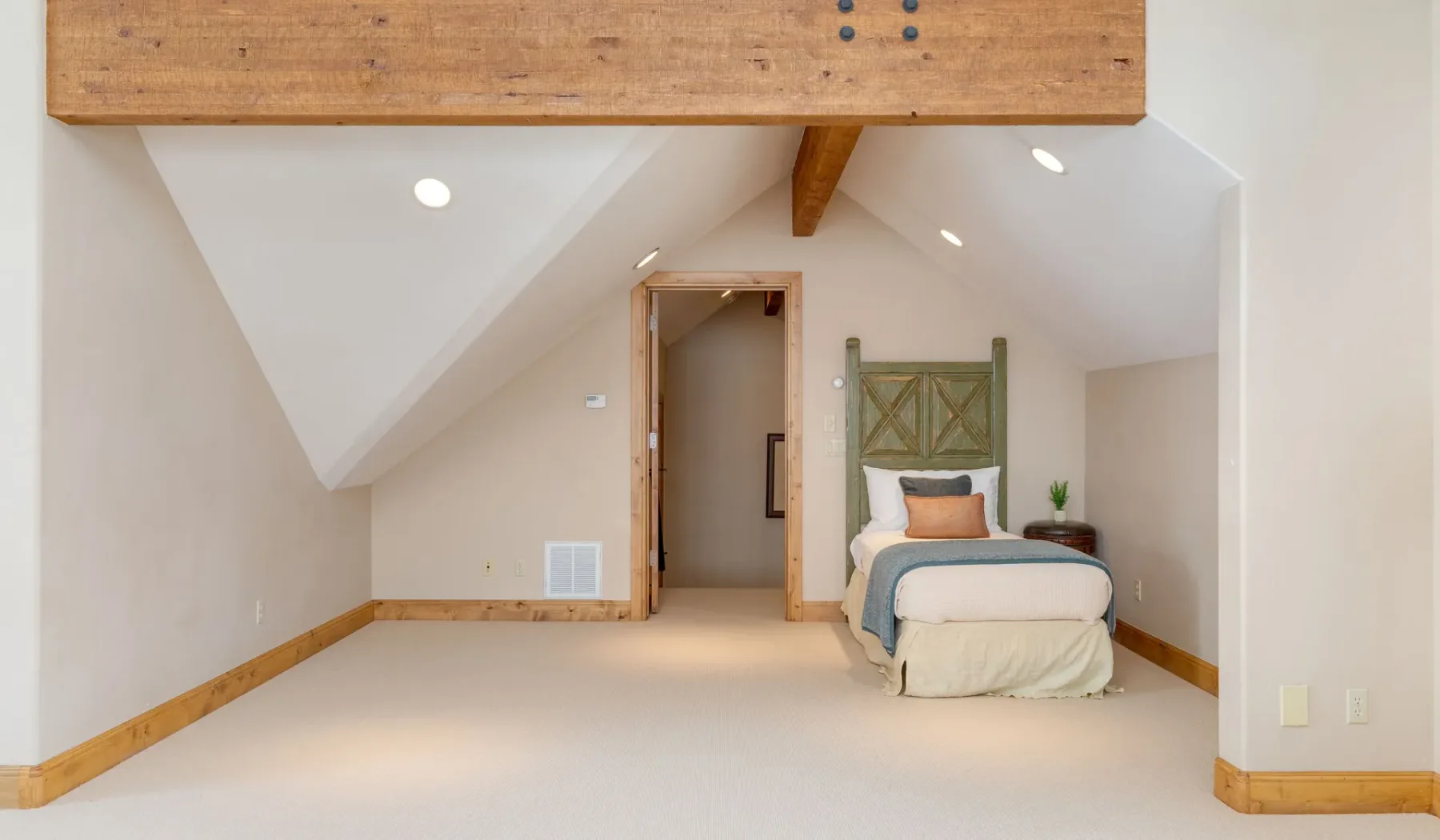 Un dormitorio abuhardillado luminoso con una cama bajo el techo inclinado.