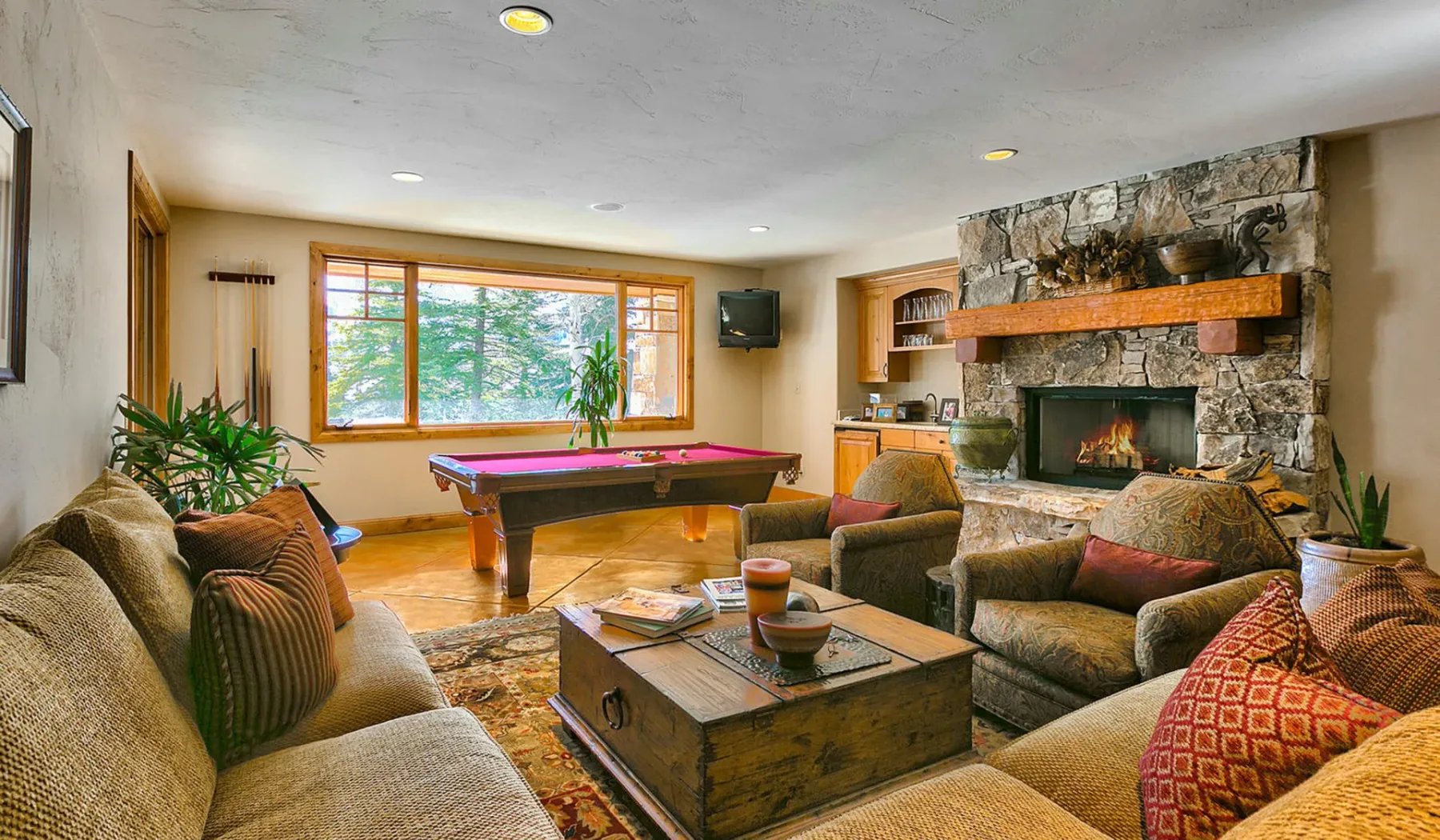 Una sala de estar con asientos, una chimenea y una mesa de billar junto a la ventana.