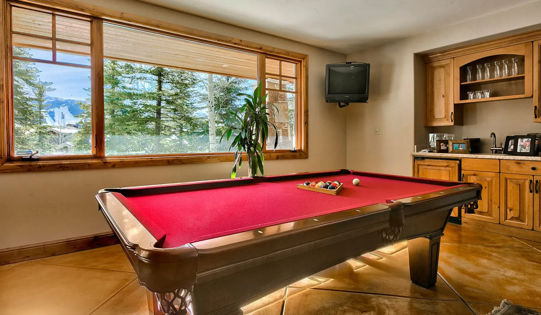Una sala de recreación cuenta con una mesa de billar de paño rojo junto a grandes ventanas.