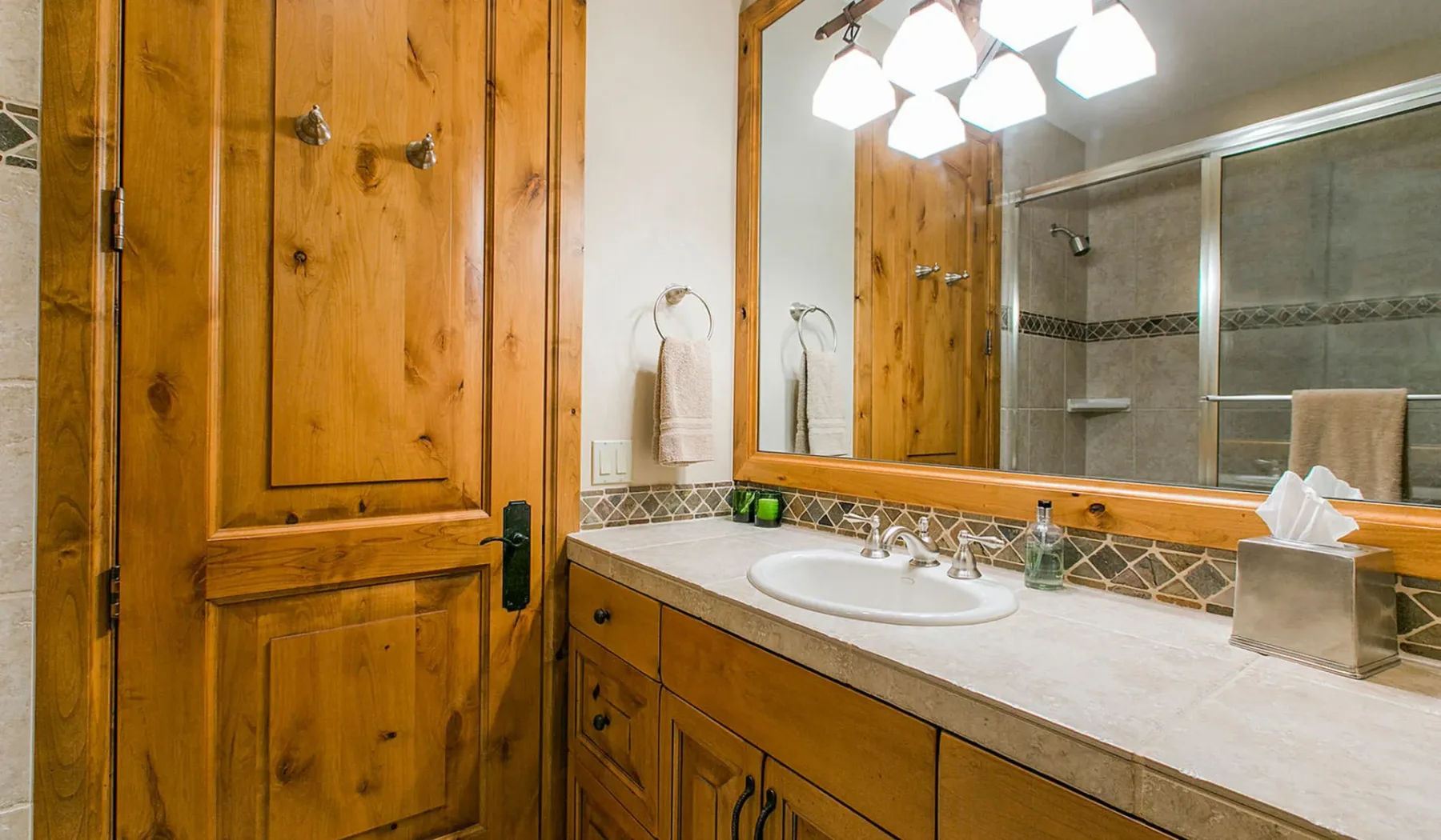 Un lavabo de baño con espejo grande junto a una puerta de madera.