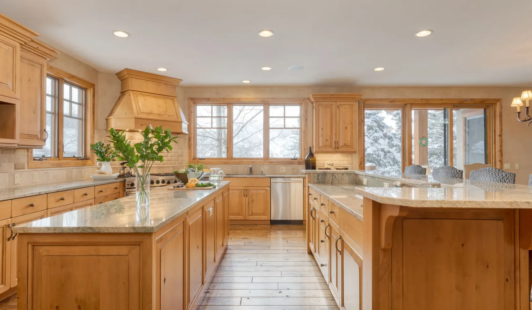 Una cocina amplia con gabinetes de madera, encimeras de piedra y ventanas grandes.
