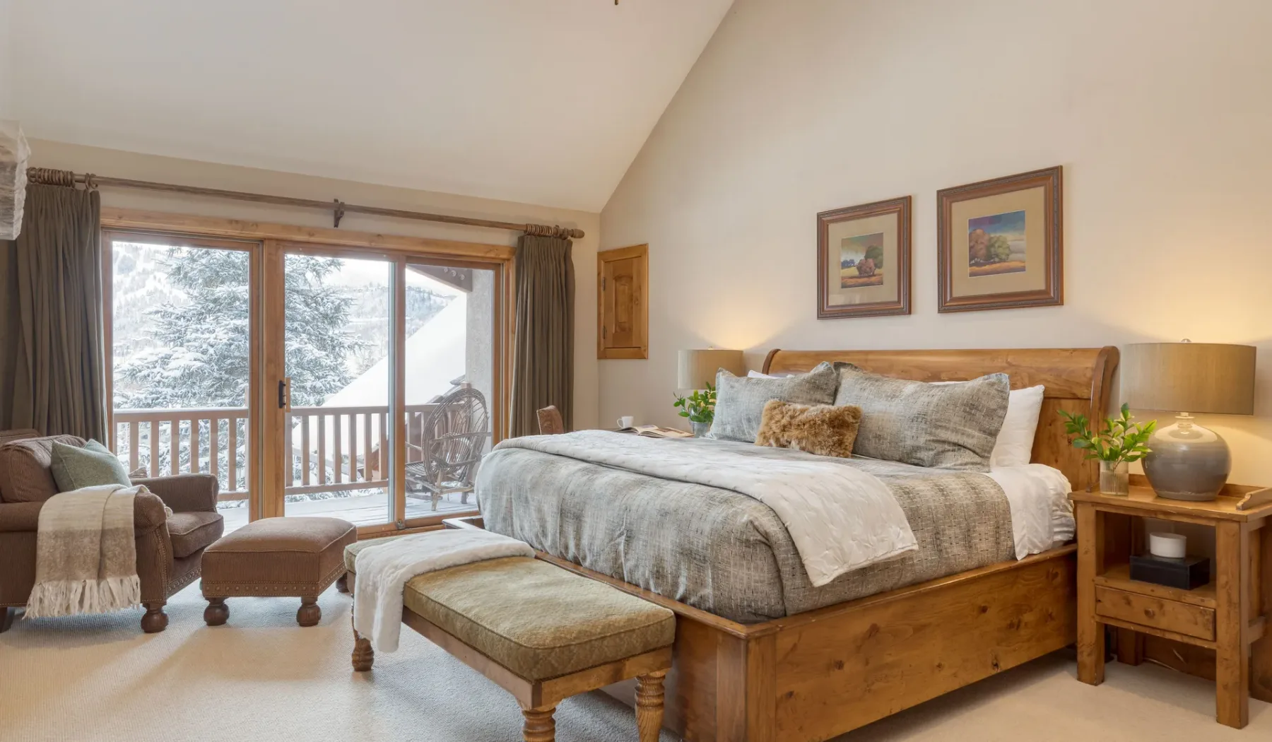 Un dormitorio con una cama de madera, asientos y puertas de vidrio que dan a un balcón.