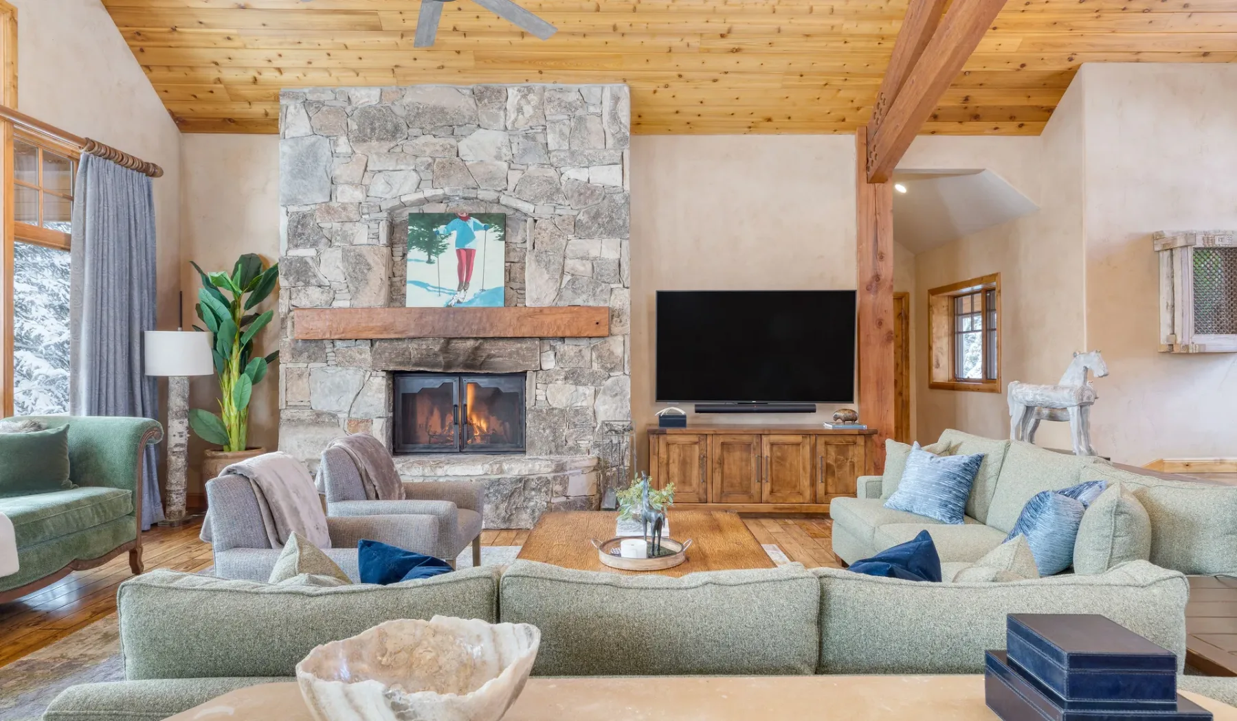 Una sala de estar con asientos dispuestos alrededor de una chimenea de piedra y un televisor.