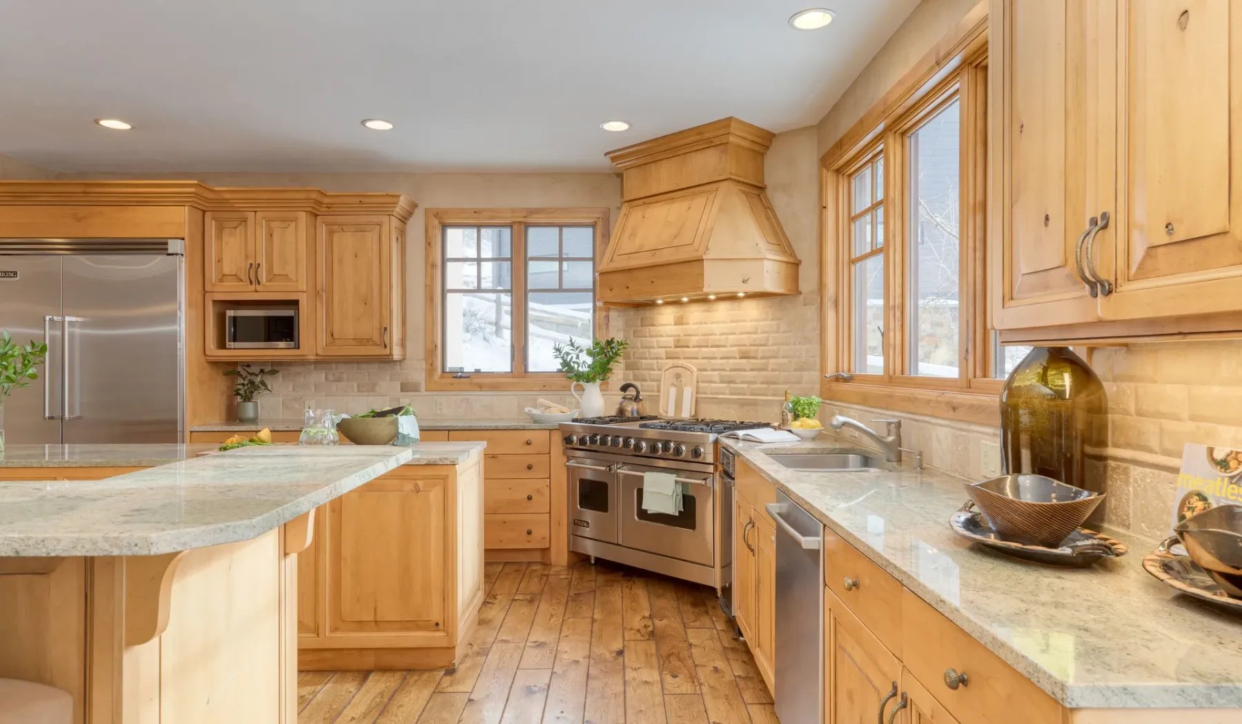 Una cocina amplia con gabinetes de madera, encimeras de piedra y una estufa de acero inoxidable.