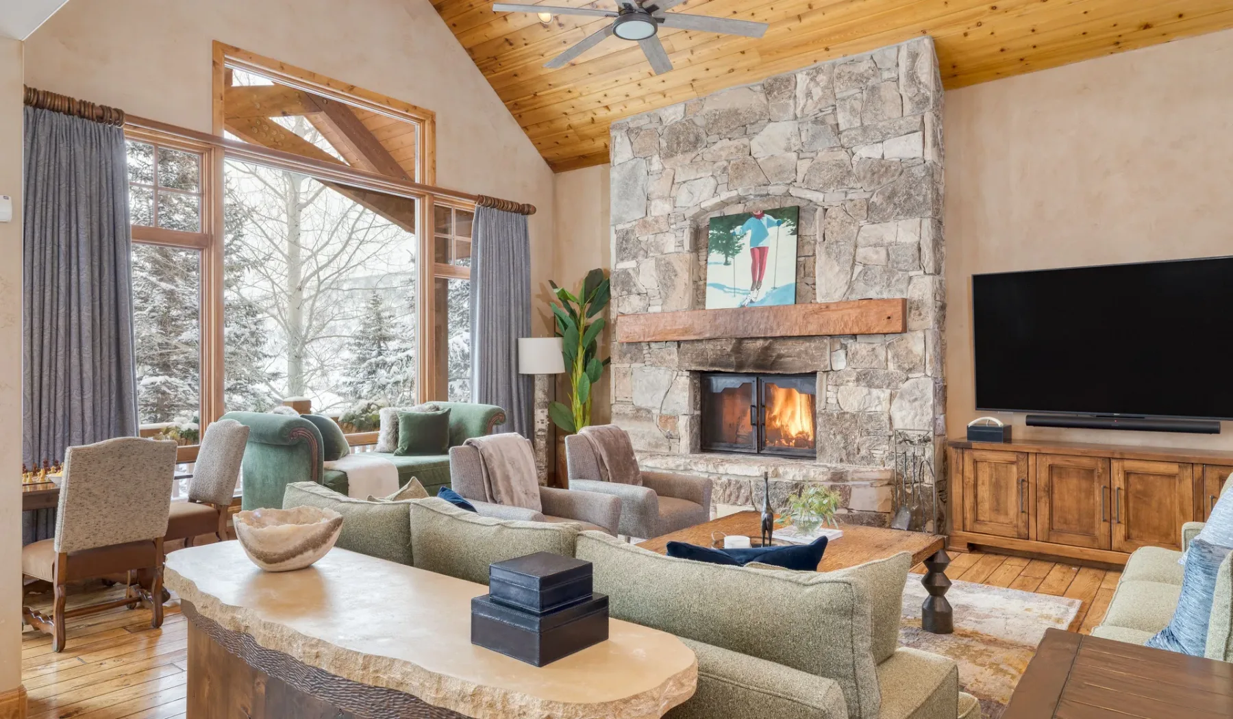 Una sala de estar con asientos alrededor de una chimenea de piedra y un televisor.