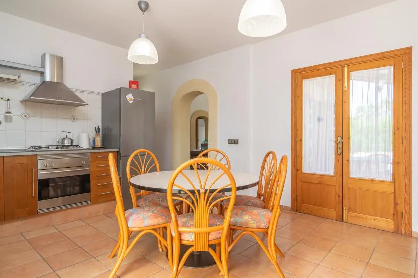 A kitchen and dining area with a round table and wooden chairs.