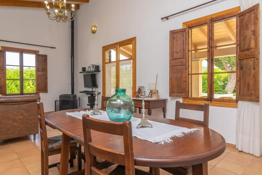 A dining room with a wooden table and open windows overlooking greenery.