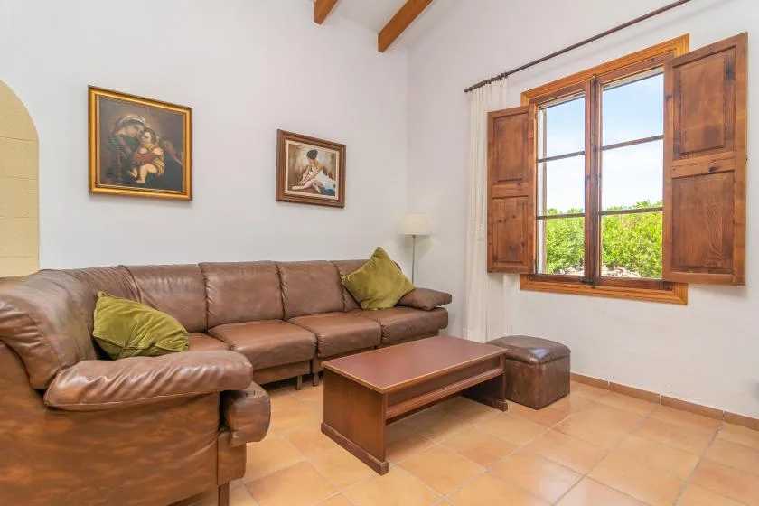 A living room with leather seating and a wooden coffee table beside a window.