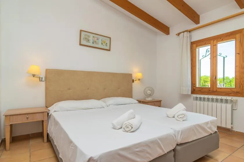 A bedroom with a large bed beneath a framed picture and a window.