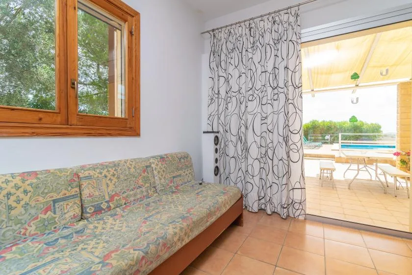 A tiled sitting area with a patterned daybed beside an open patio.
