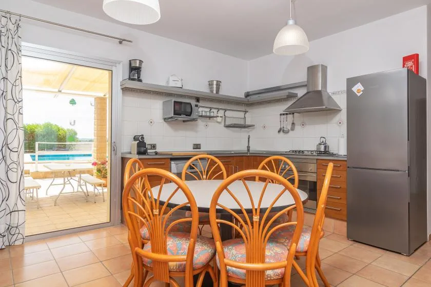A bright kitchen and dining area with a table beside glass doors opening onto a patio.