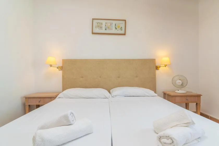 A bedroom with a double bed, bedside tables, and wall lamps.