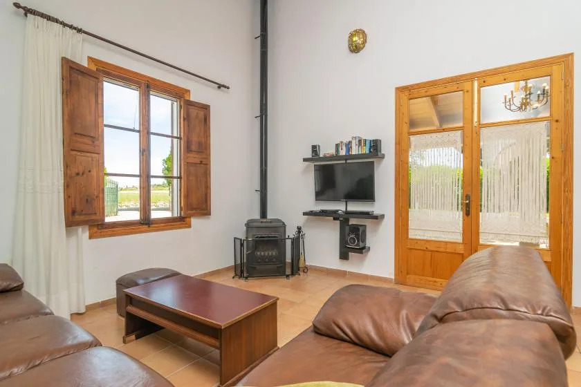 A living room with leather seating, a wood coffee table, and a television.