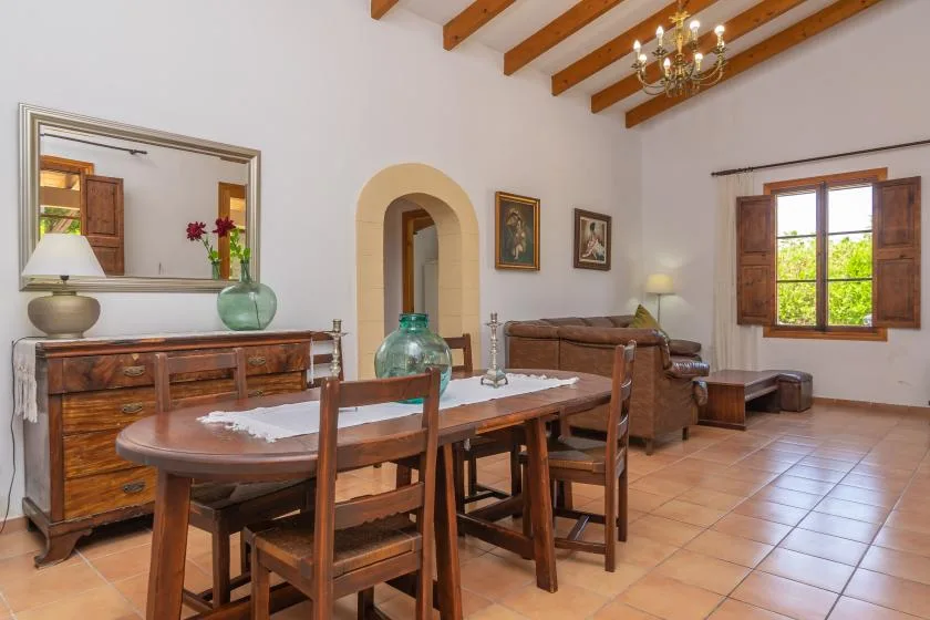A dining area with a wooden table and chairs beneath exposed ceiling beams.