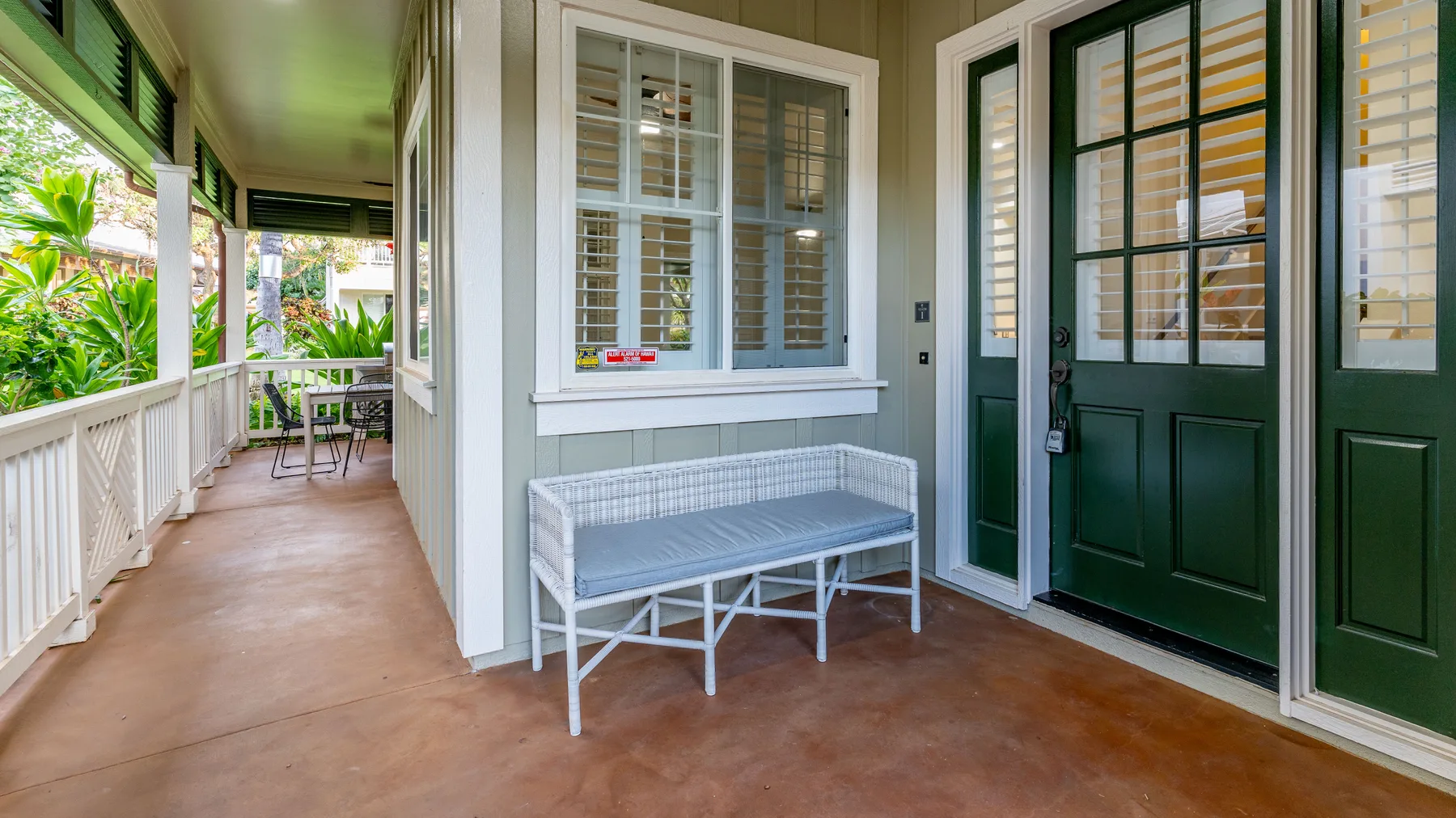 A covered porch with a bench beside a dark green entry door.