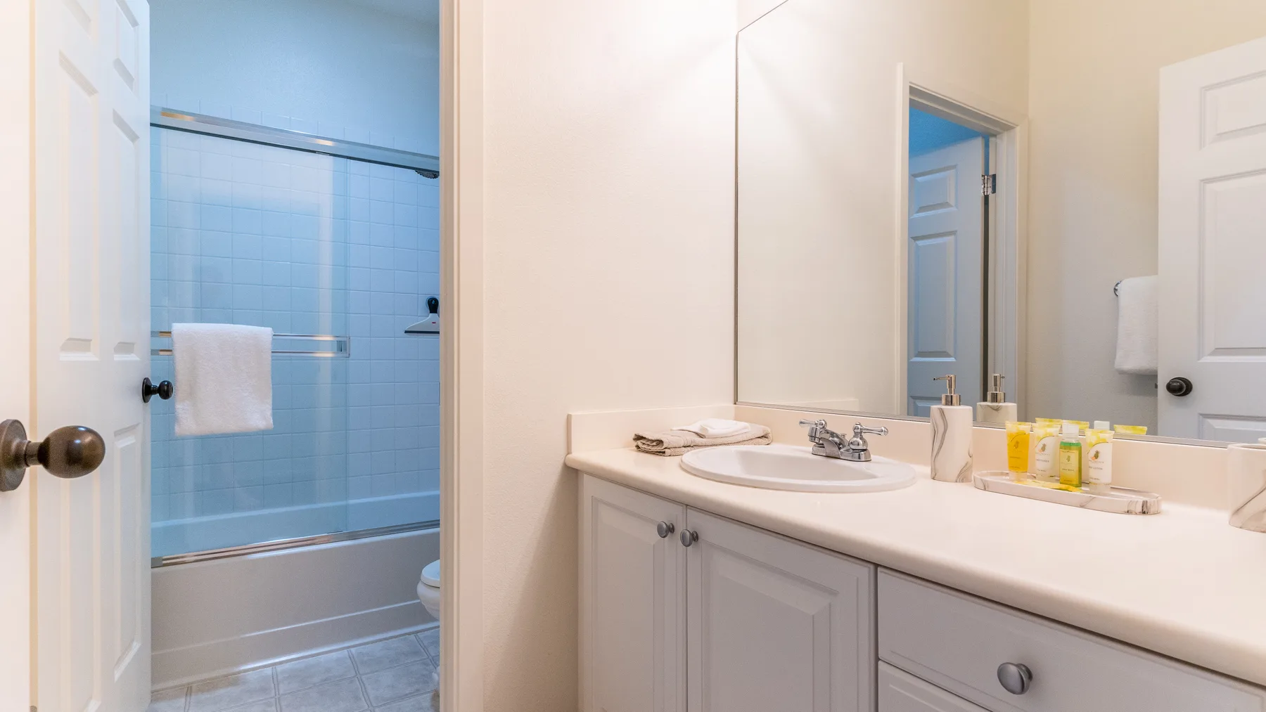 A bathroom vanity with a sink stands beside a tiled shower area.