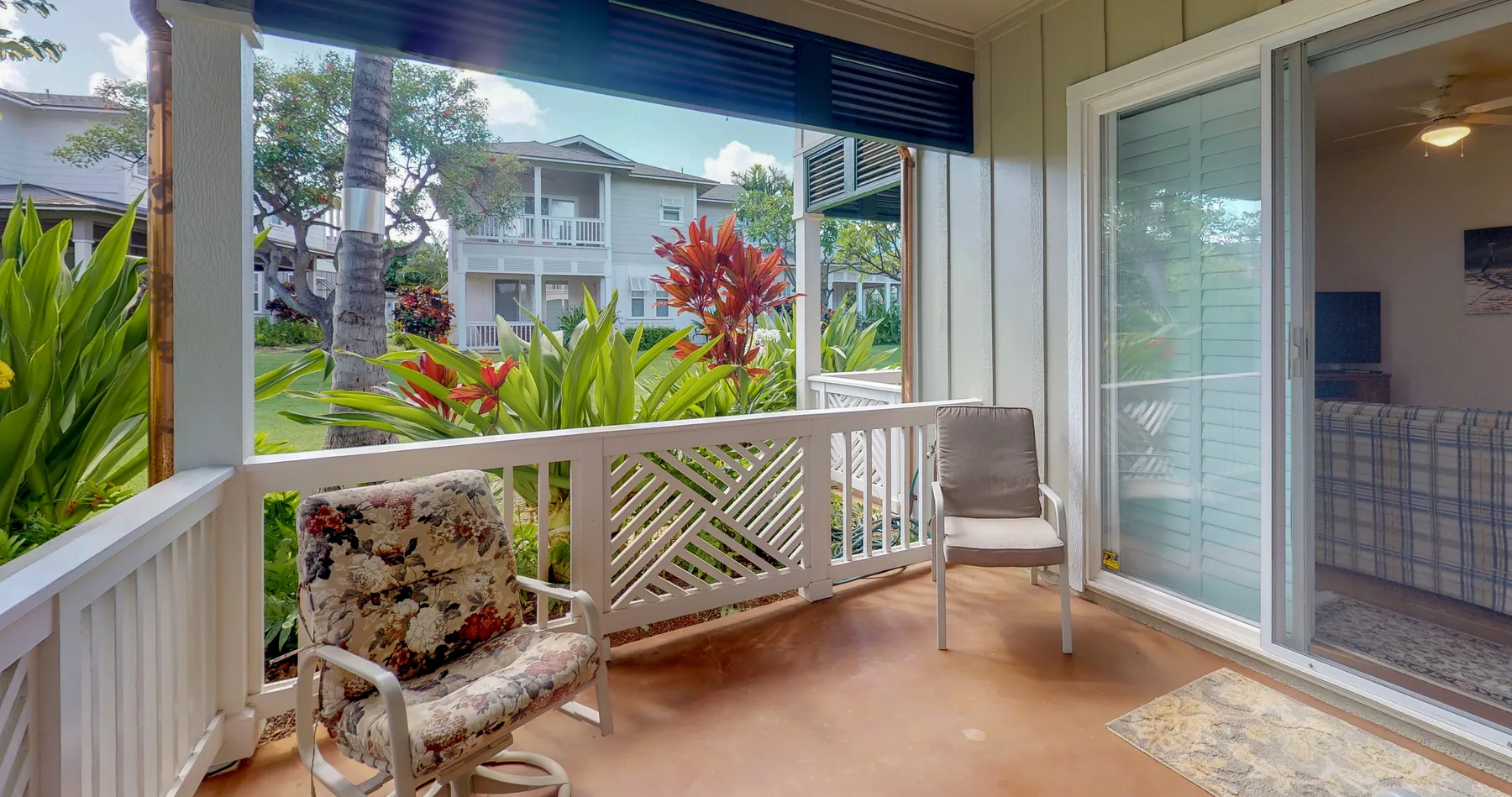 A covered patio with seating overlooks a lush garden.