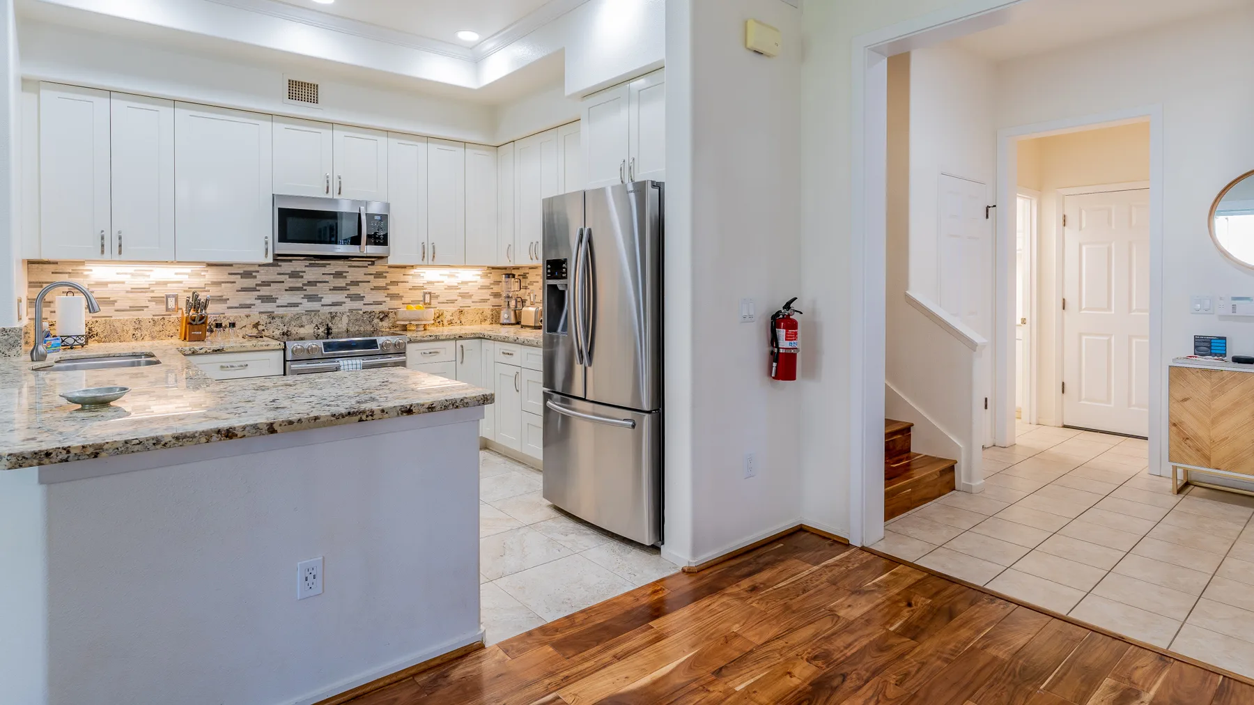 A bright kitchen with white cabinetry, a central island, and stainless-steel appliances.
