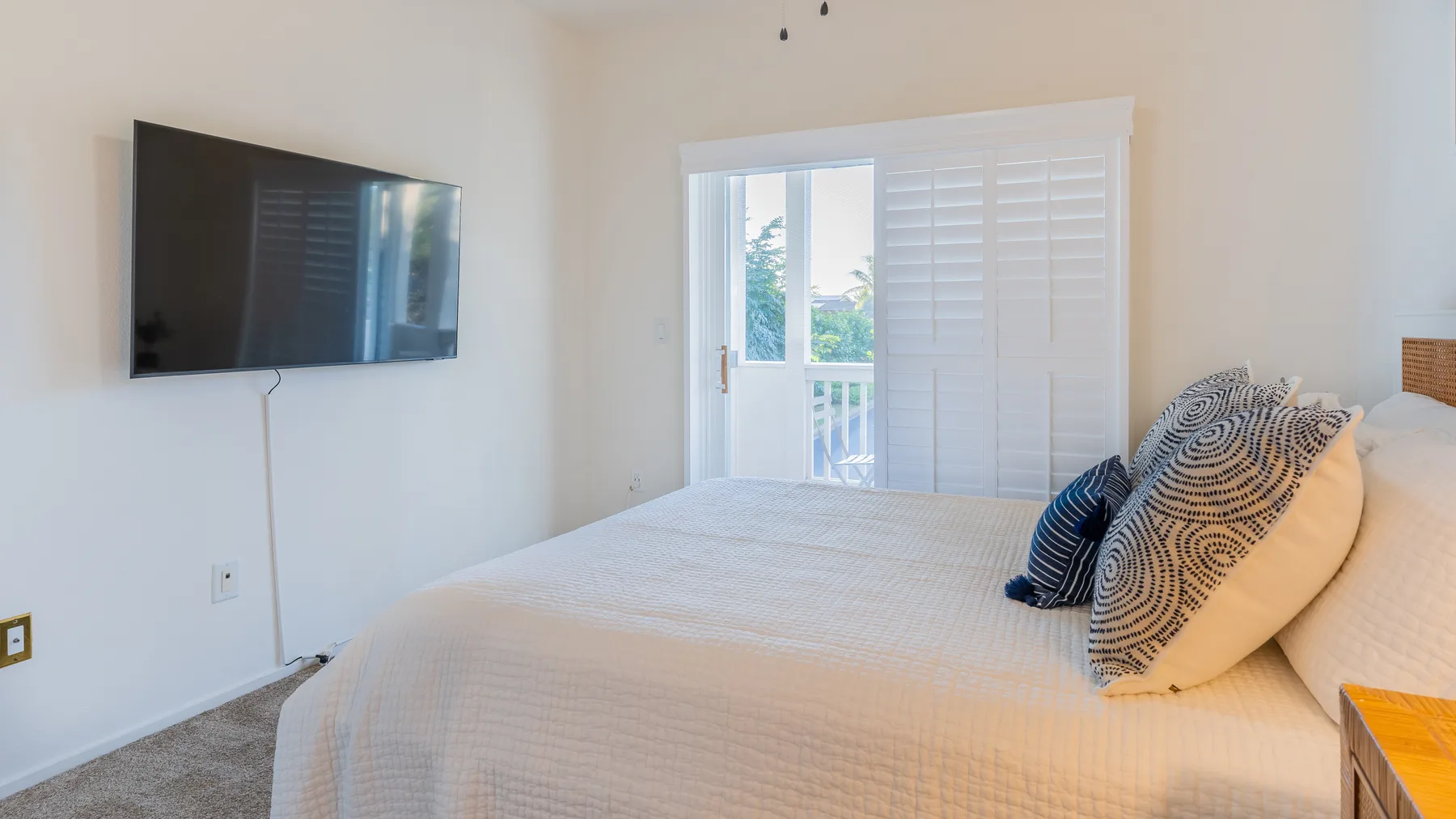A bright bedroom with a bed and a wall-mounted television.