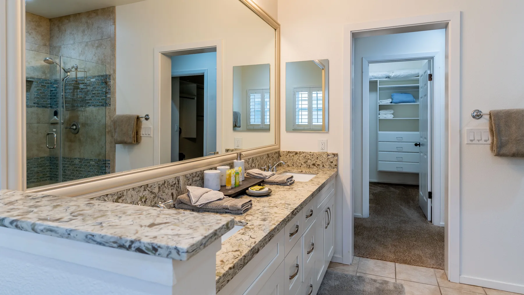 A bathroom vanity with a wide countertop sits beside a glass-enclosed shower.