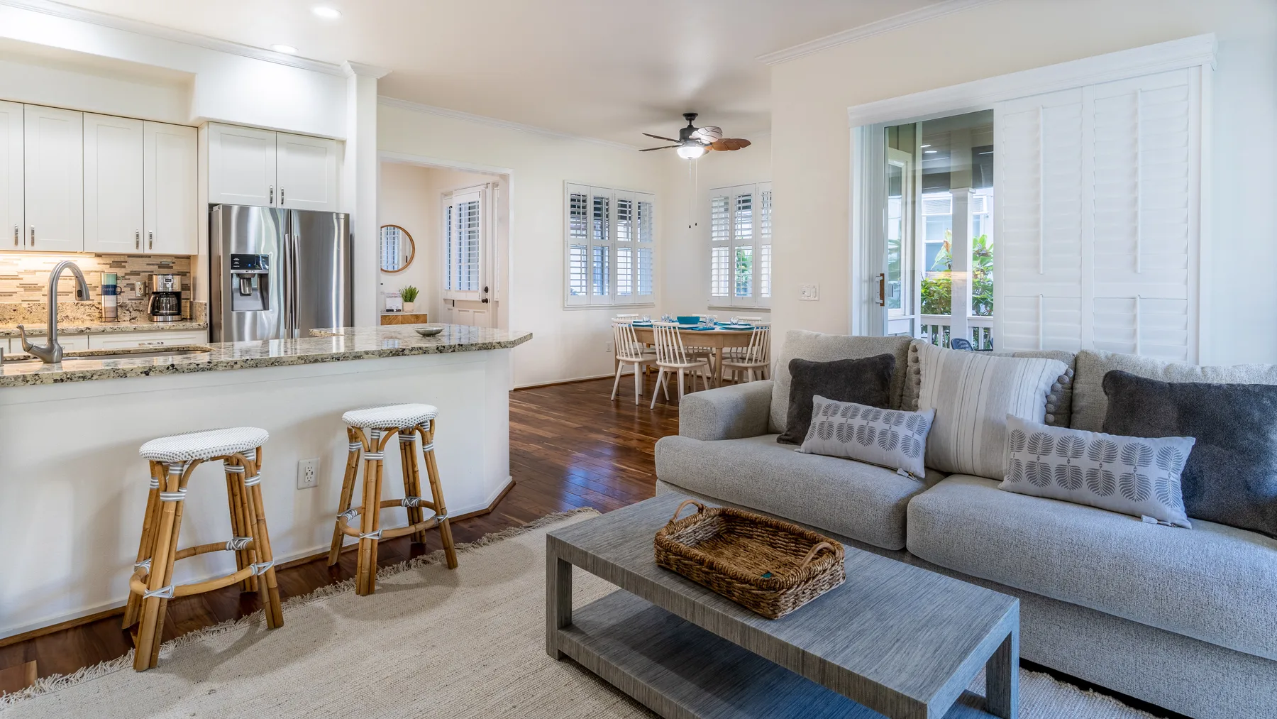 An open-plan living room and kitchen with a dining table and gray seating.