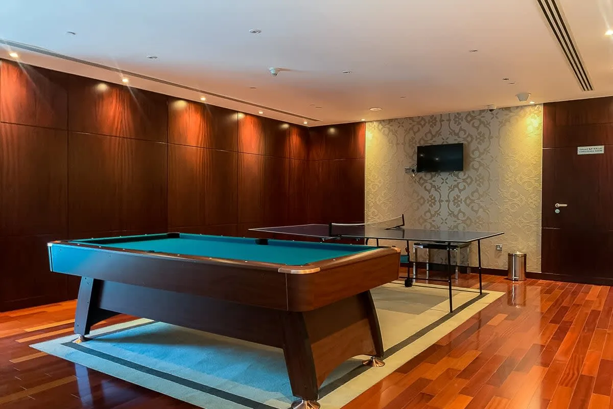 Una sala de billar con una mesa de pool y un televisor en la pared.