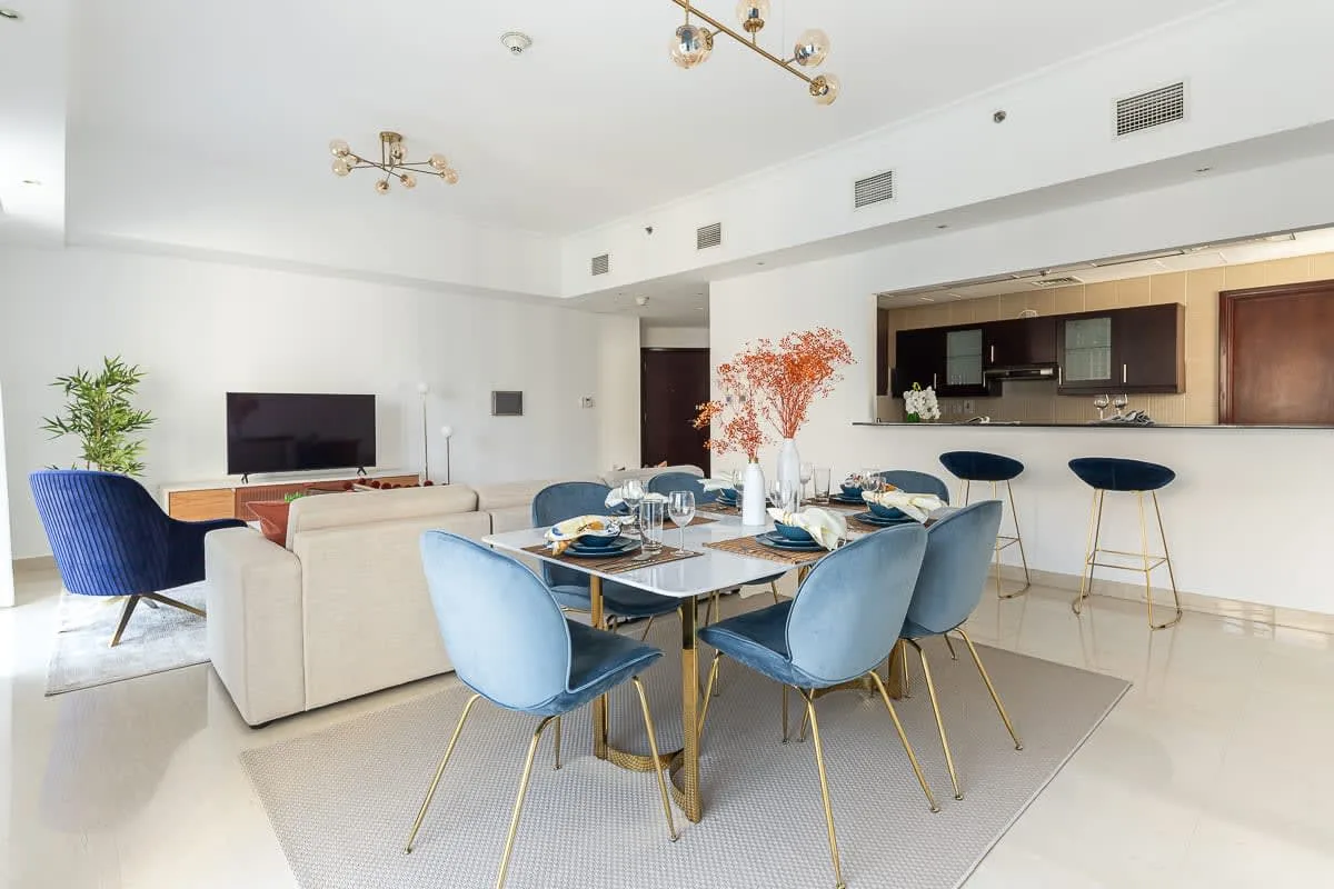 Un comedor con la mesa puesta y una cocina al fondo.