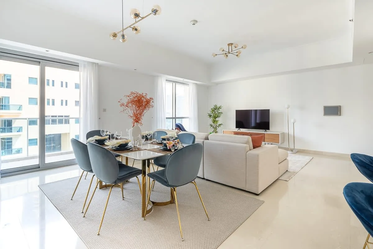 Una luminosa sala-comedor diáfana con mesa, asientos y un televisor.